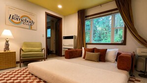 Habitació d'hotel amb un llit gran, una cadira, una finestra amb cortines, un senyal a la paret i un radiador.