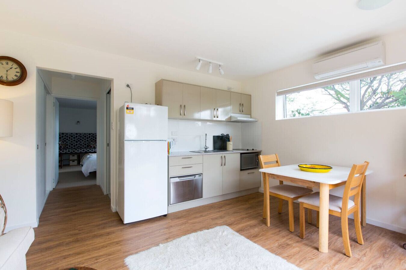 Une cuisine compacte équipée d’un réfrigérateur, d’un four, d’un four à micro-ondes et d’un coin repas avec une table et des chaises.