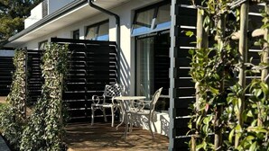 A modern house with a patio area featuring outdoor furniture and a wooden fence. - Blix Inn (Stellenbosch)