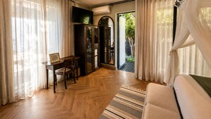A room with a wooden floor, a sofa, a table with chairs, a ceiling fan, and a view through a glass door to an outdoor area. - Blix Inn (Stellenbosch)