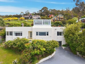 A modern two-story house with a flat roof, large windows, and a covered outdoor area.