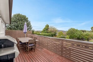 A deck with a grill, wooden table, chairs, and a purple umbrella. - `Landport` Charming Historic Home, Modern Comforts (New Town)