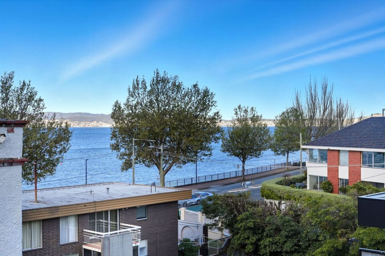 Ett bostadsområde med utsikt över havet, en asfalterad gångväg och moderna byggnader.