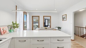 A modern kitchen with white cabinetry, a large island, and a view to the outside.