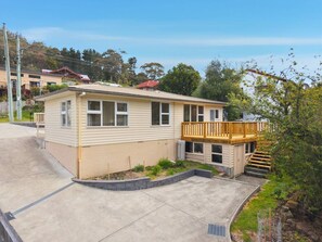 A single-story house with a front porch, a small deck, and a concrete driveway. - Cosy South Hobart Getaway (Dynnyrne)