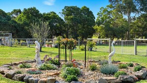 Ein Garten mit Statuen, einem eingezäunten Bereich und Bäumen.