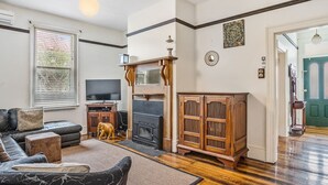 A living room with a fireplace, sofa, and television. - Roope Cottage-Location, Free WiFi & Parking (New Town)