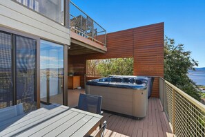 Un balcone con vasca idromassaggio, terrazza in legno e vista sul mare.