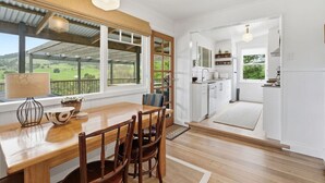 Eine Küche mit Holztisch und -stühlen, einem Fenster mit Blick ins Grüne und einem hellen Interieur.
