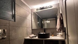 A narrow bathroom with a toilet, sink, and mirror. - Modern One-Bedroom Apartment in Kypseli - 1000 Mbps Fiber Wi-Fi (Athina)