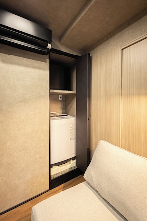 Ein gemütlicher Raum mit Bett, einer integrierten Waschmaschine und einem Holzschrank.