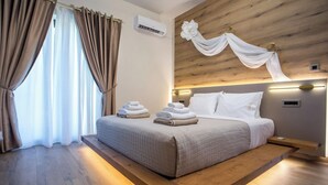 A modern bedroom with a wooden headboard, a bed with neatly folded towels, and a large window with curtains. - Kallisti Luxury Villa (Rhodes)