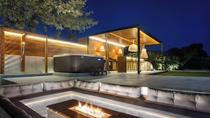 A modern outdoor living area with a fire pit, seating, and a hot tub. - Kallisti Luxury Villa (Rhodes)