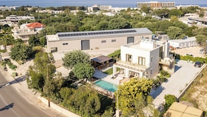 A modern building with a swimming pool, solar panels, and a view of the sea. - Kallisti Luxury Villa (Rhodes)