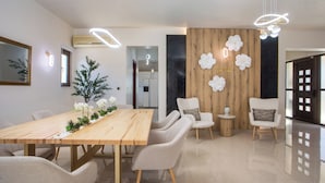 A modern dining area with a wooden table, white chairs, and a decorative wall with flowers. - Kallisti Luxury Villa (Rhodes)