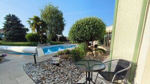A patio area with a pool, outdoor furniture, and a stone pathway.