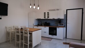A compact kitchen with white cabinetry, a wooden countertop, a black microwave, and a black toaster. There are three white chairs around a wooden table. - Sardinia Sea Relax with a Private Hot Tub Near the Beach (Quartu Sant'Elena)