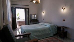 Un dormitorio con cama, escritorio, silla, cómoda, espejo y lámpara colgante.
