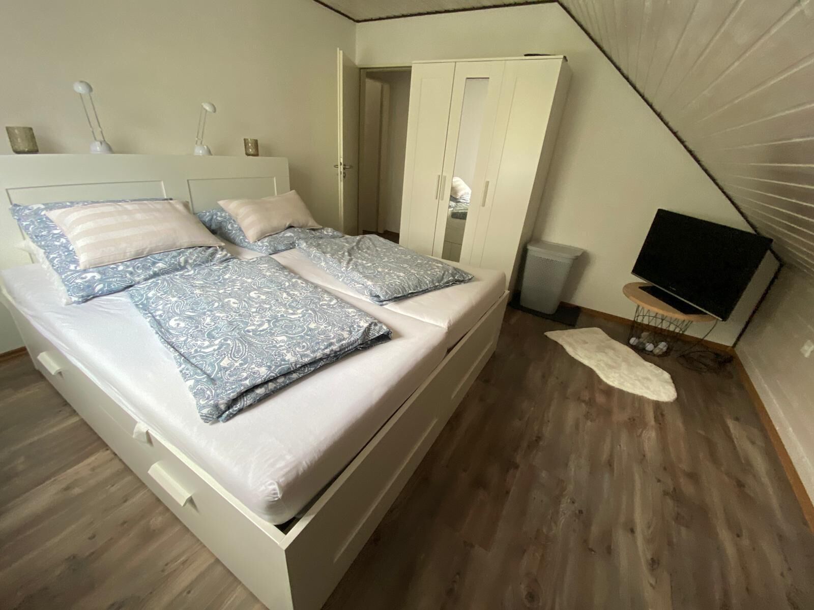 Une chambre à coucher comprenant un lit, une armoire, un téléviseur et un haut-parleur.