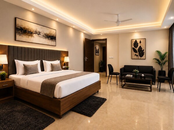 A modern hotel room with a large bed, a seating area with a sofa and chairs, a ceiling fan, and artwork on the walls. - Star Residency near Medanta Hospital (Gurugram)