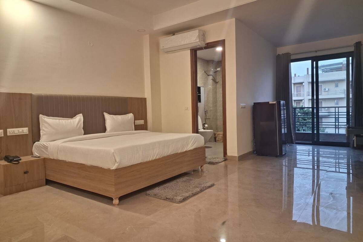 Ein modernes Hotelzimmer mit einem großen Bett, Nachttischen, einem Badezimmer mit Dusche und einem Balkon mit Blick.