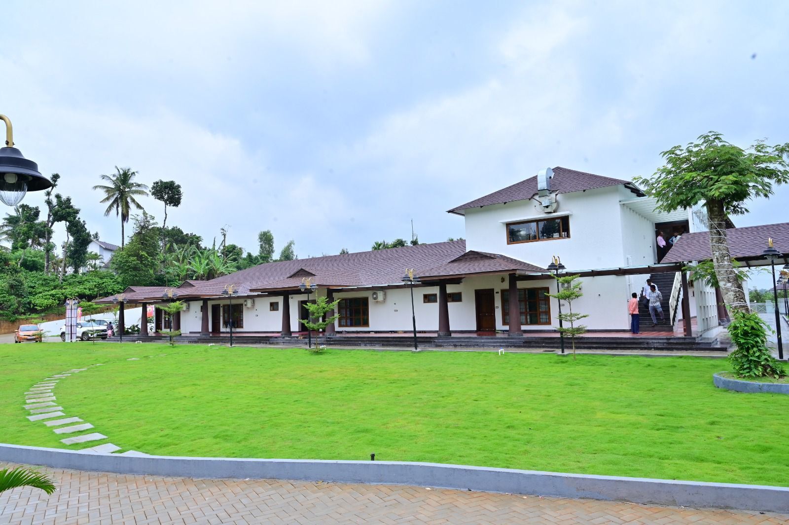 A white building with multiple rooms, a covered walkway, and a well-maintained lawn.