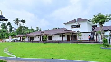 A white building with multiple rooms, a covered walkway, and a well-maintained lawn.