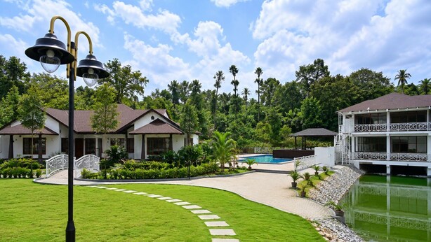 A resort with a swimming pool, a white gazebo, and a well-maintained lawn.