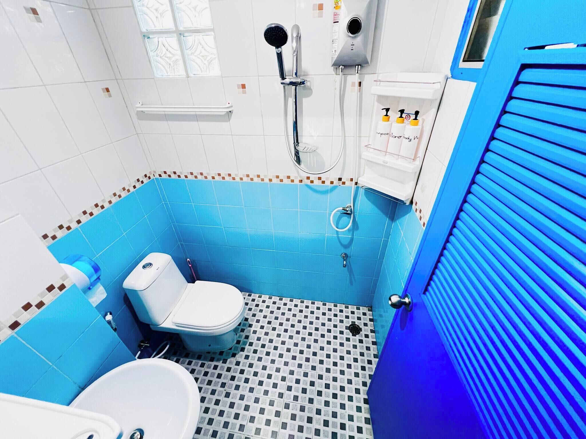 A bathroom with a white toilet, a shower, and a sink.