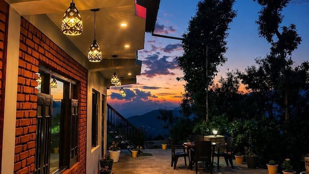 A covered outdoor area with hanging lights, potted plants, and a view of the sky.