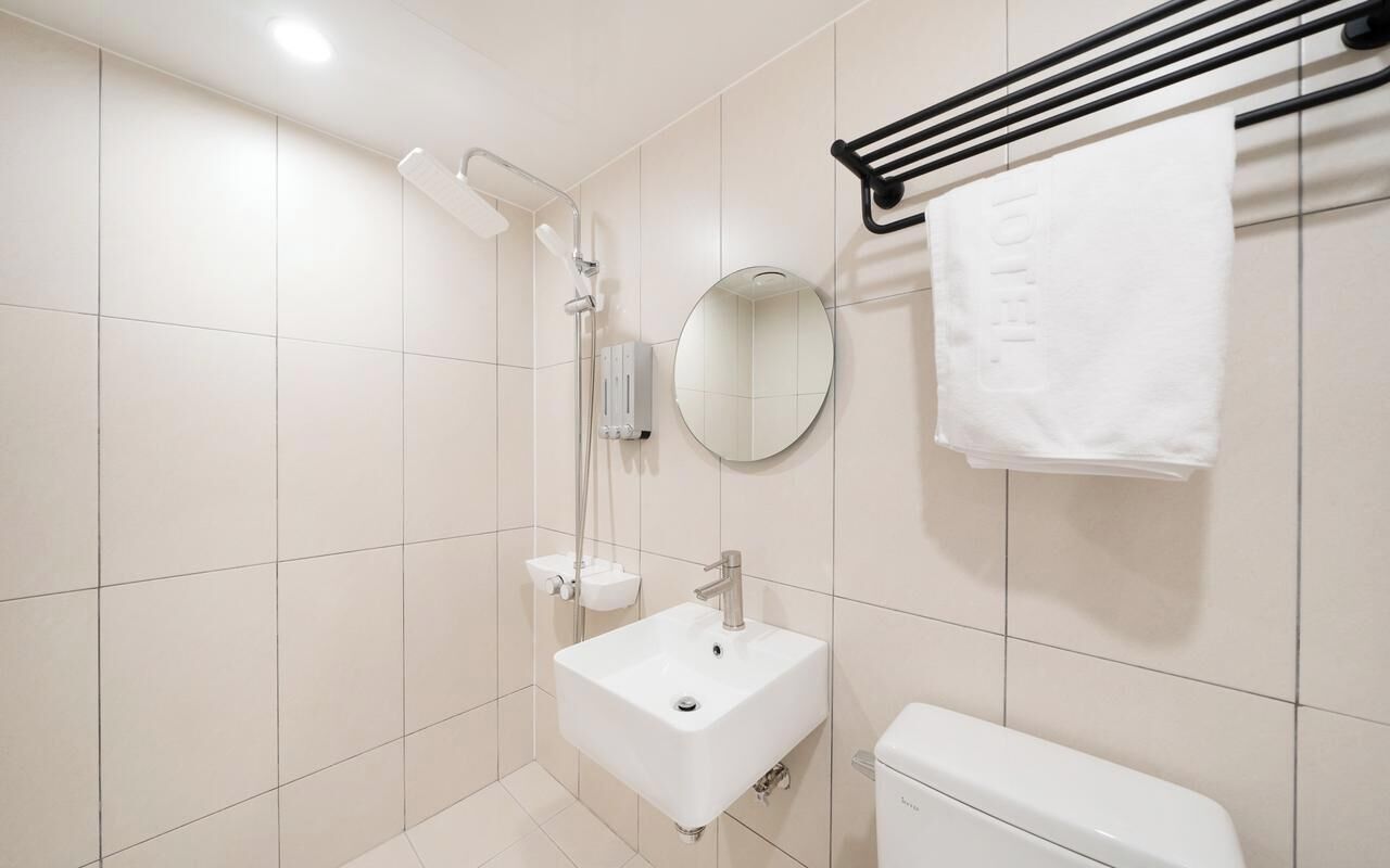 A modern bathroom with a white sink, a toilet, a shower, and a towel rack.