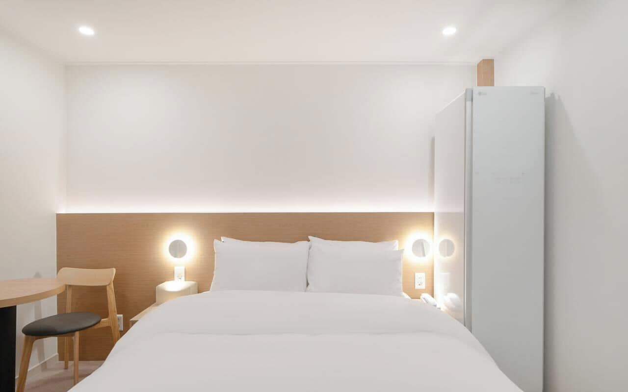 Una camera d'albergo con un letto, due abat-jour, una scrivania e una sedia.