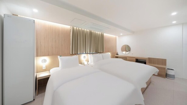 Una habitación de hotel moderna con una cama grande, mesitas de noche, un espejo y un armario empotrado.