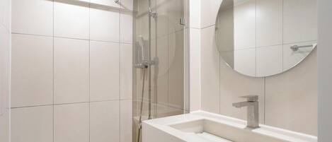 A modern bathroom with a shower, a sink, and a mirror.