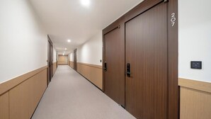 Un largo pasillo estrecho con puertas de madera y suelo alfombrado.