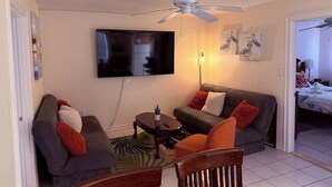 A living room with a sofa, armchair, coffee table, and a ceiling fan. - 1R Lido Key - Steps to Beach, Walk to St. Armand's (Sarasota)