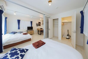 A hotel room with two beds, a desk, a chair, a TV, a closet, and a vacuum cleaner. - Granduo Shirokane 2 (Minato City)
