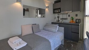 Quarto compacto com uma cama, pequeno espaço de cozinha, micro-ondas e pia.