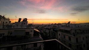 Paisagem urbana ao pôr do sol, com vários edifícios e telhados.