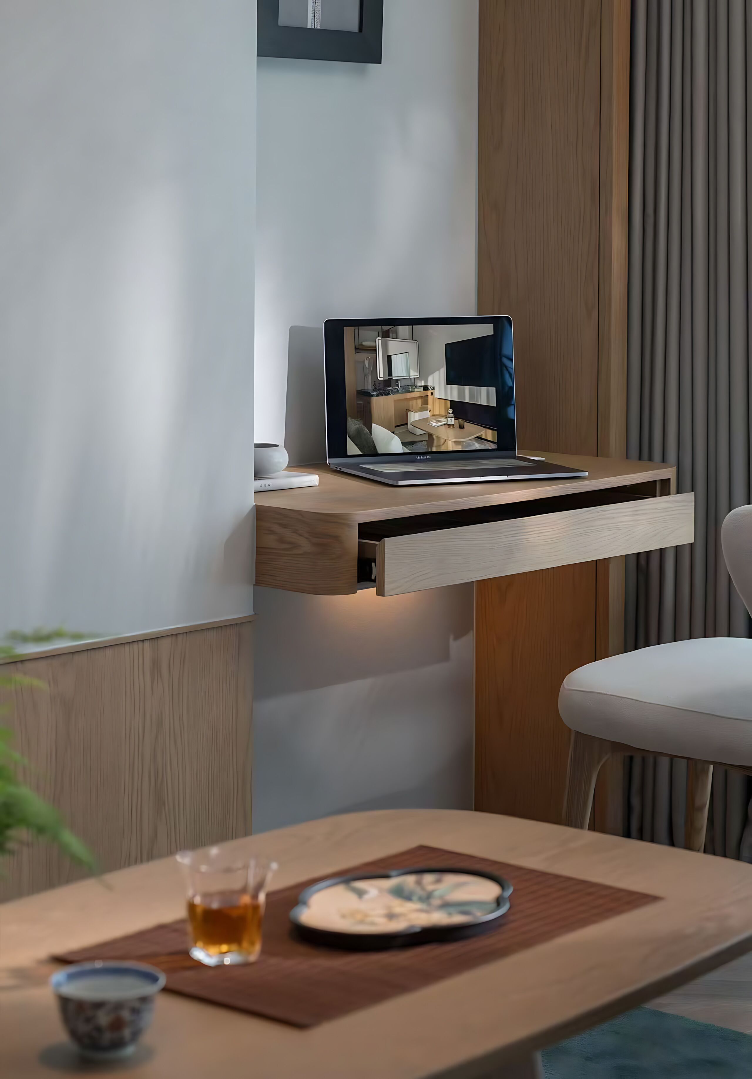 A modern kitchen with a laptop on a wooden shelf, a dining table with a glass of tea, and a chair.