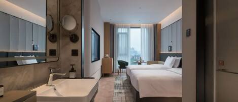 A modern hotel room with a large bed, a separate bathroom with a sink, a mirror, and a view of the city.