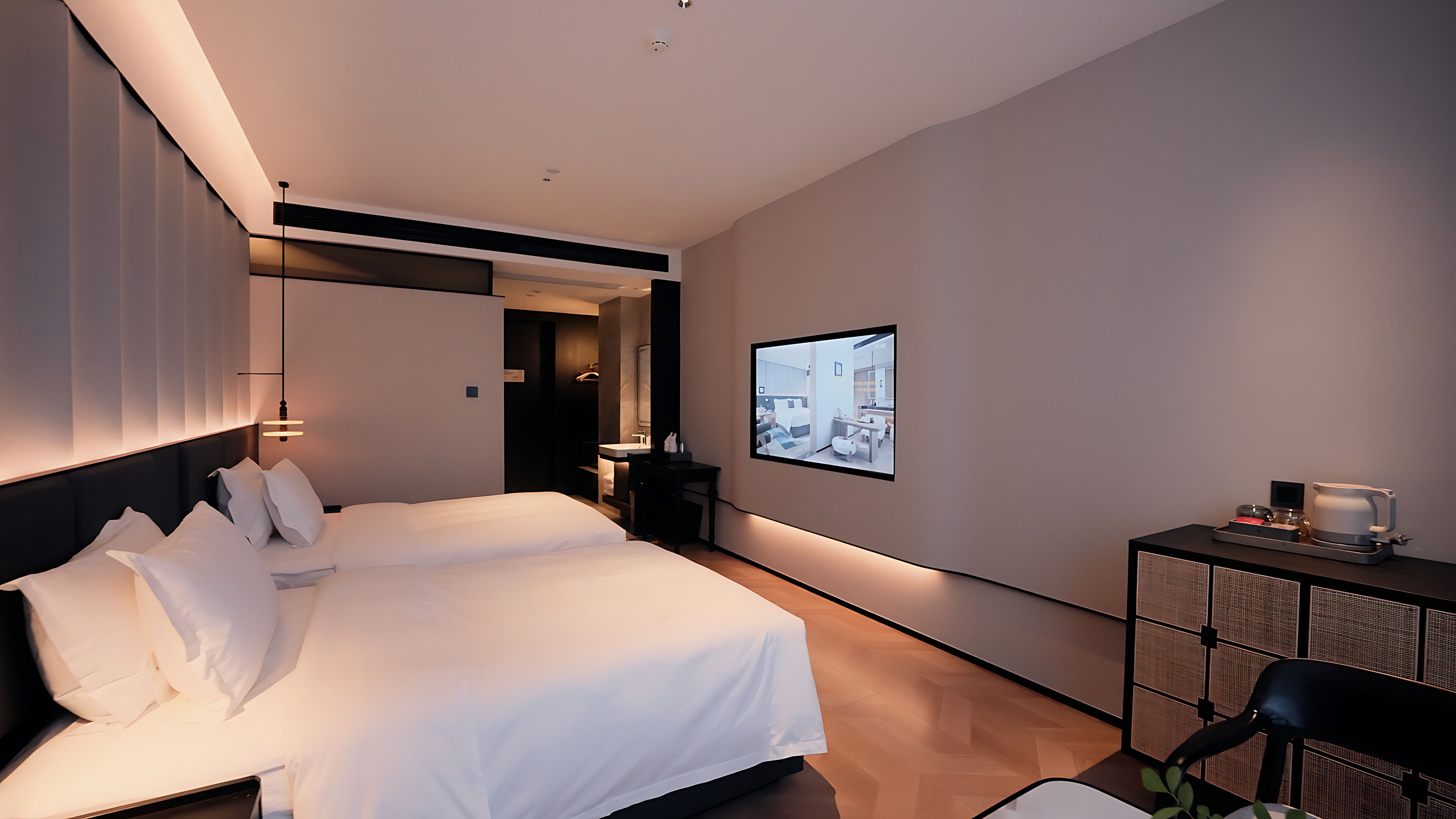 A modern hotel room with a large bed, a desk, a chair, and a television on the wall.