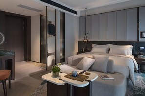 Et moderne hotelværelse med en seng, et natbord og et lille siddeområde med en plante og pynt.