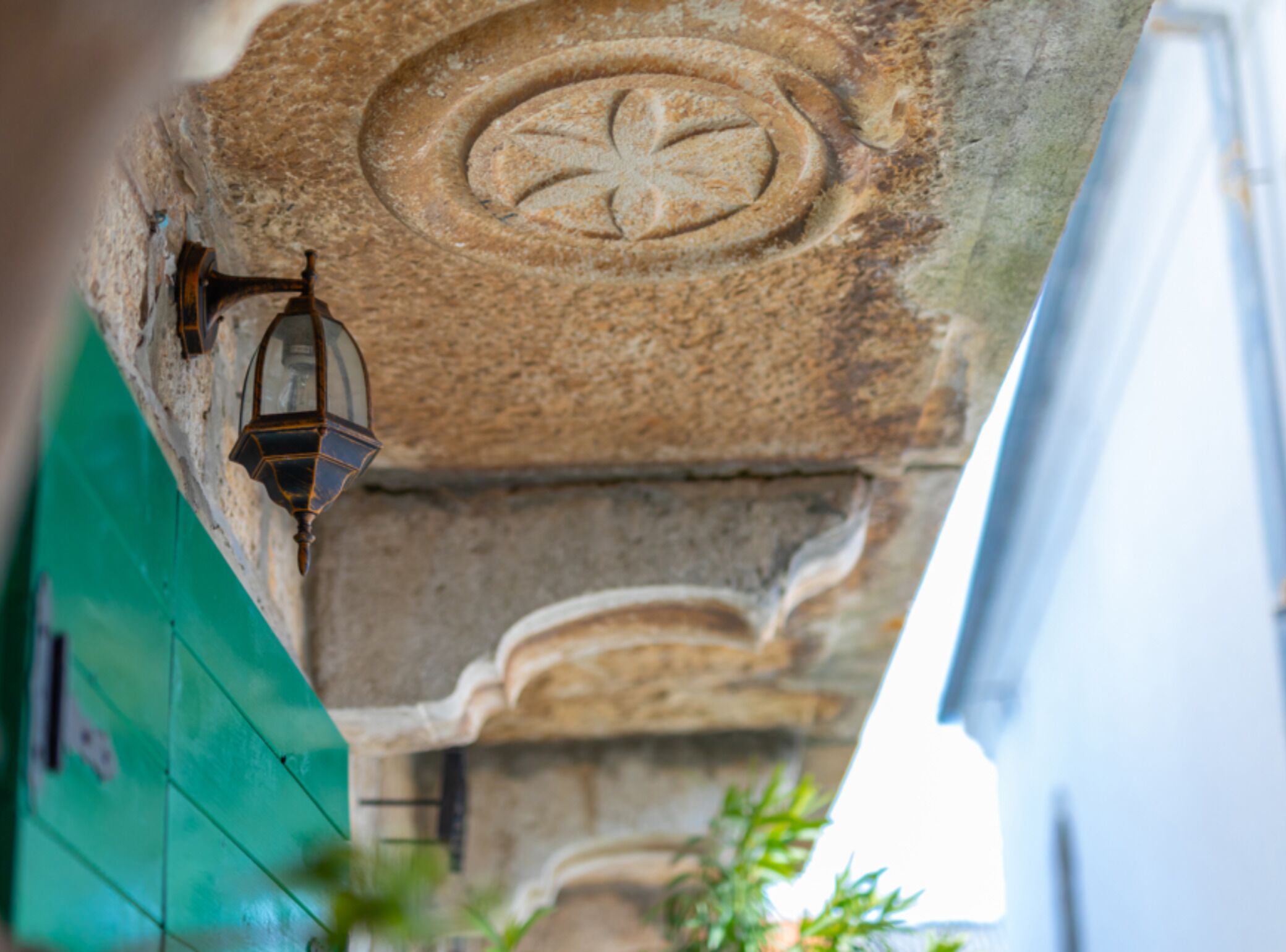 A stone wall with a carved emblem and a hanging lantern.