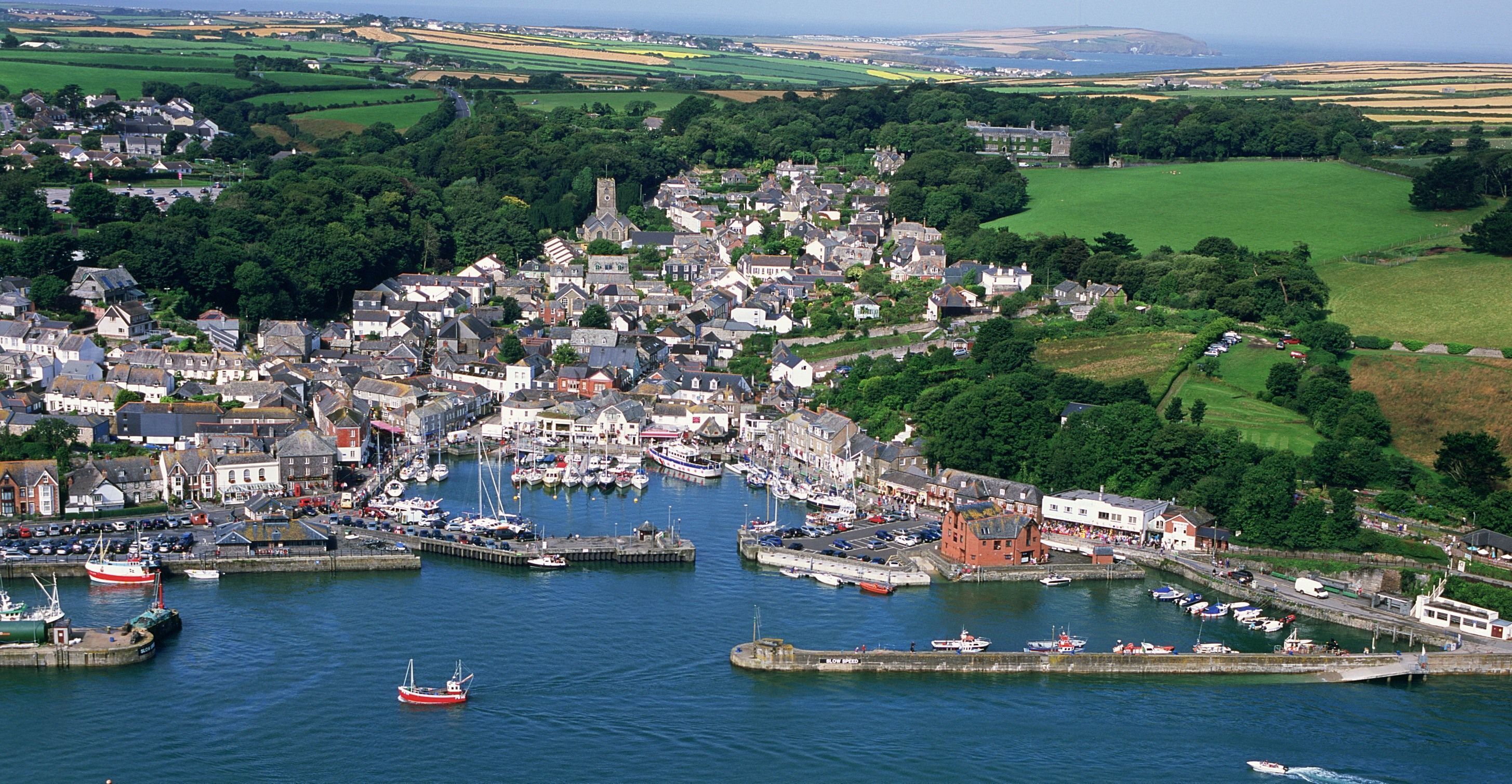 A coastal town with a harbor, boats, and a castle-like structure.