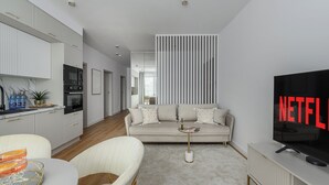 Un salon moderne comprenant un canapé, une table basse, un téléviseur et un coin cuisine.