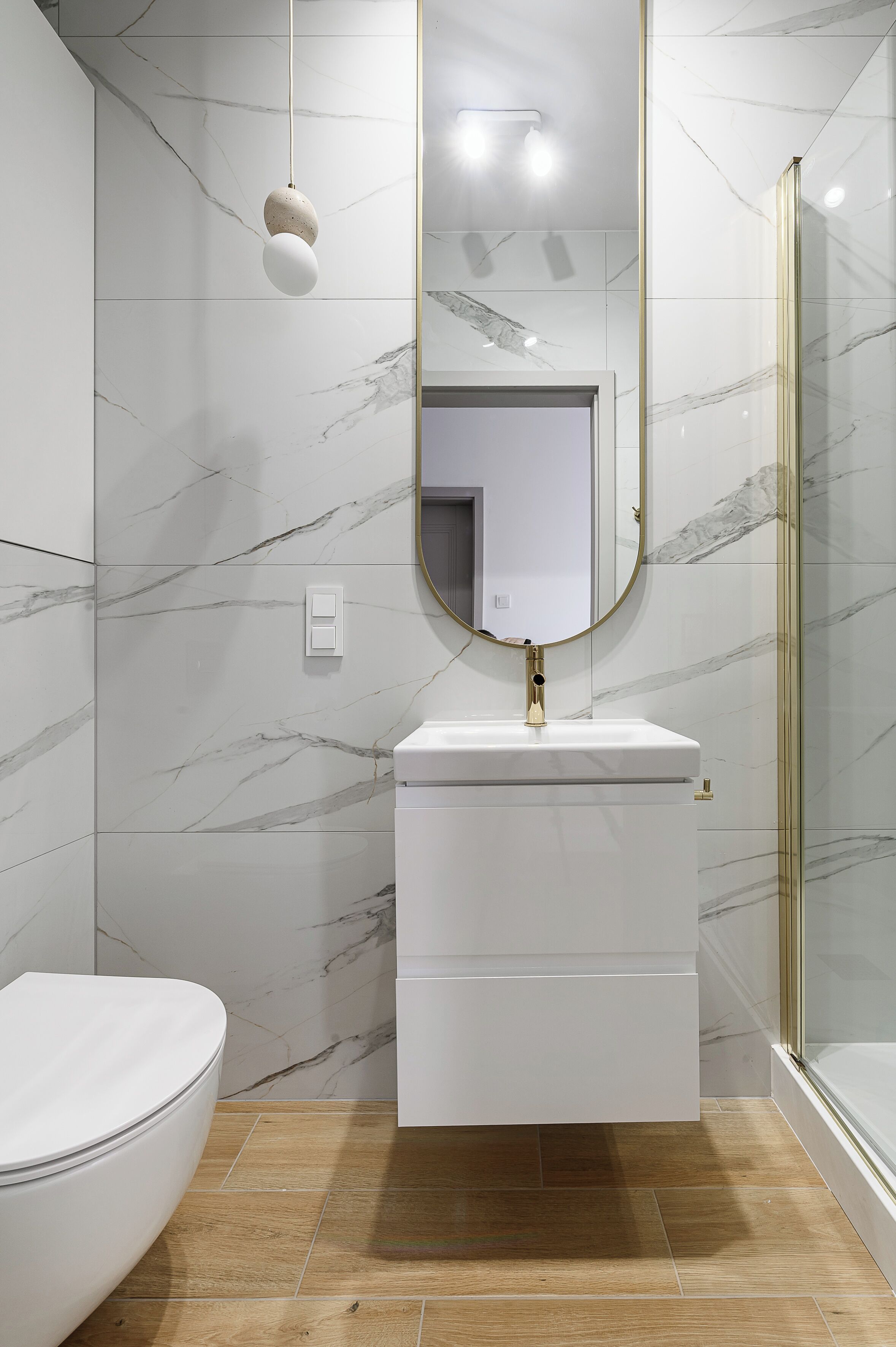Un baño con inodoro, un lavabo con grifo dorado y un espejo con marco dorado.