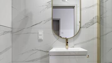 Un baño con inodoro, un lavabo con grifo dorado y un espejo con marco dorado.