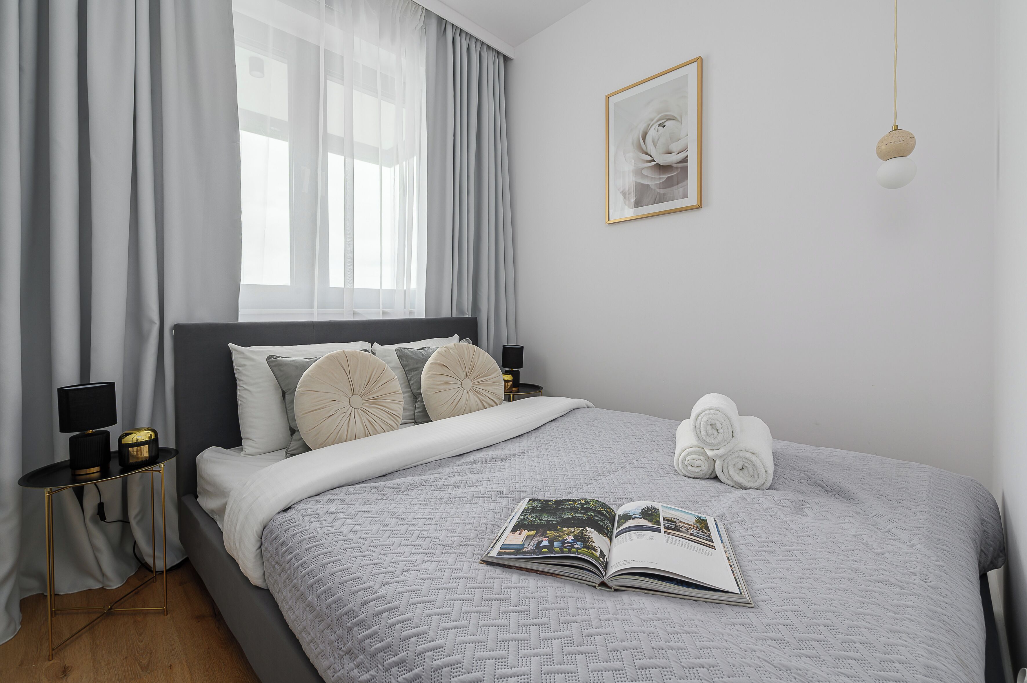 A neatly made bed with a patterned bedspread, a bedside table with a lamp, and a framed picture on the wall.
