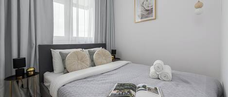 A neatly made bed with a patterned bedspread, a bedside table with a lamp, and a framed picture on the wall.